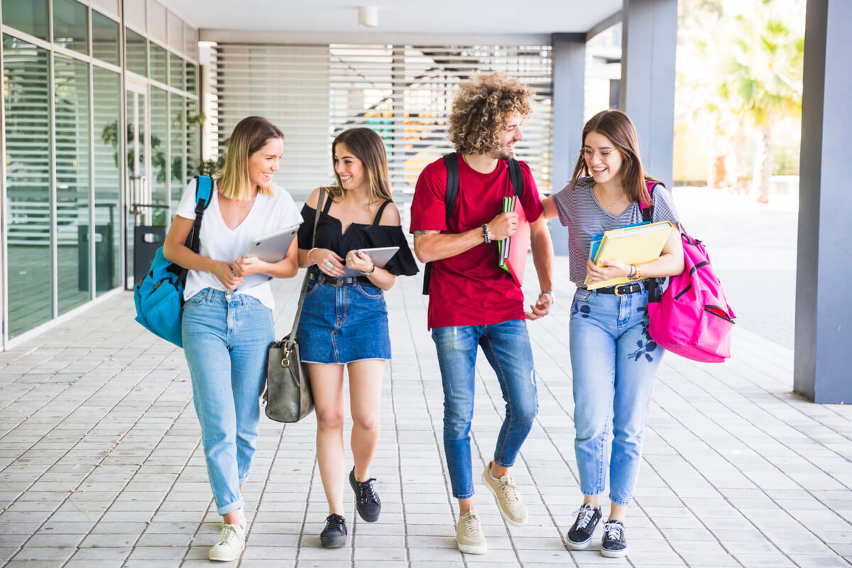 Calouro da faculdade andando no campus com suas amigas.