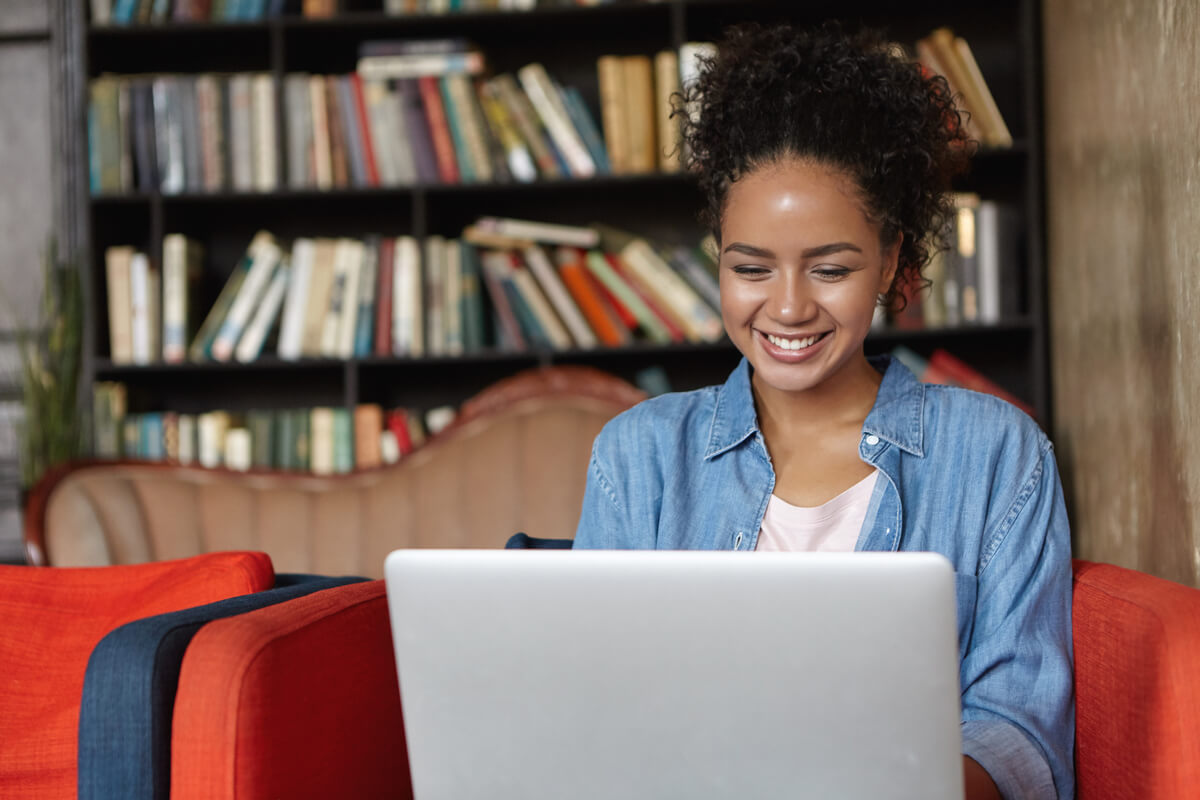Mulher jovem com seu computador realizando a rematrícula da faculdade.