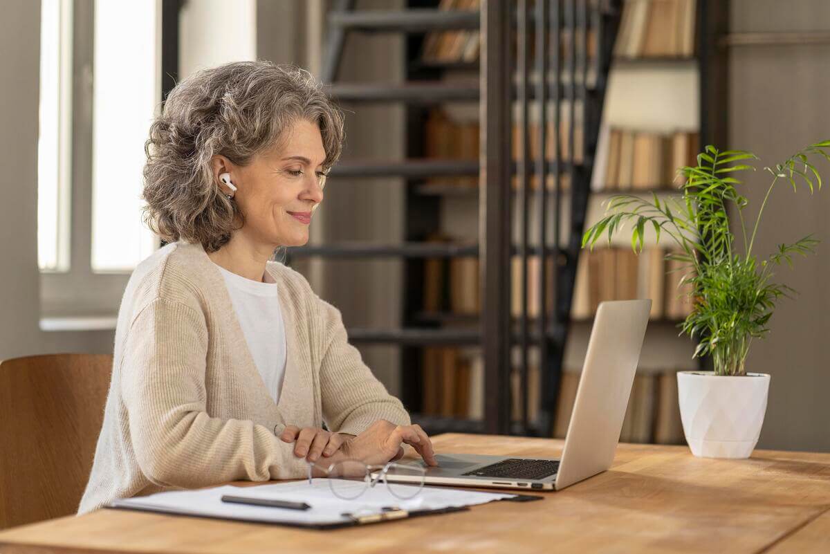 Mulher mais velha estudando pelo computador devido ao lifelong learning da empresa que trabalha.