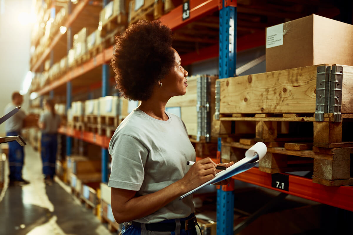 Mulher negra fazendo um relatório após estudar logística e ter conquistado o primeiro trabalho.